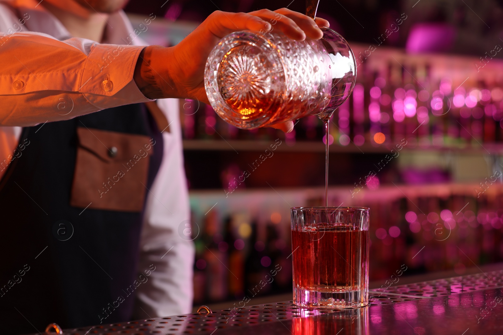 Photo of Bartender making fresh alcoholic cocktail at counter in bar, closeup