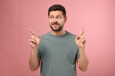Photo of Emotional man crossing his fingers on pink background