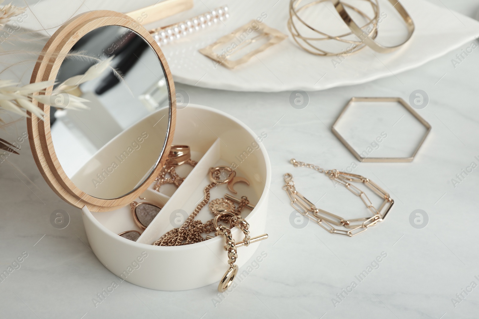 Photo of Jewelry box with mirror and stylish golden bijouterie on white marble table