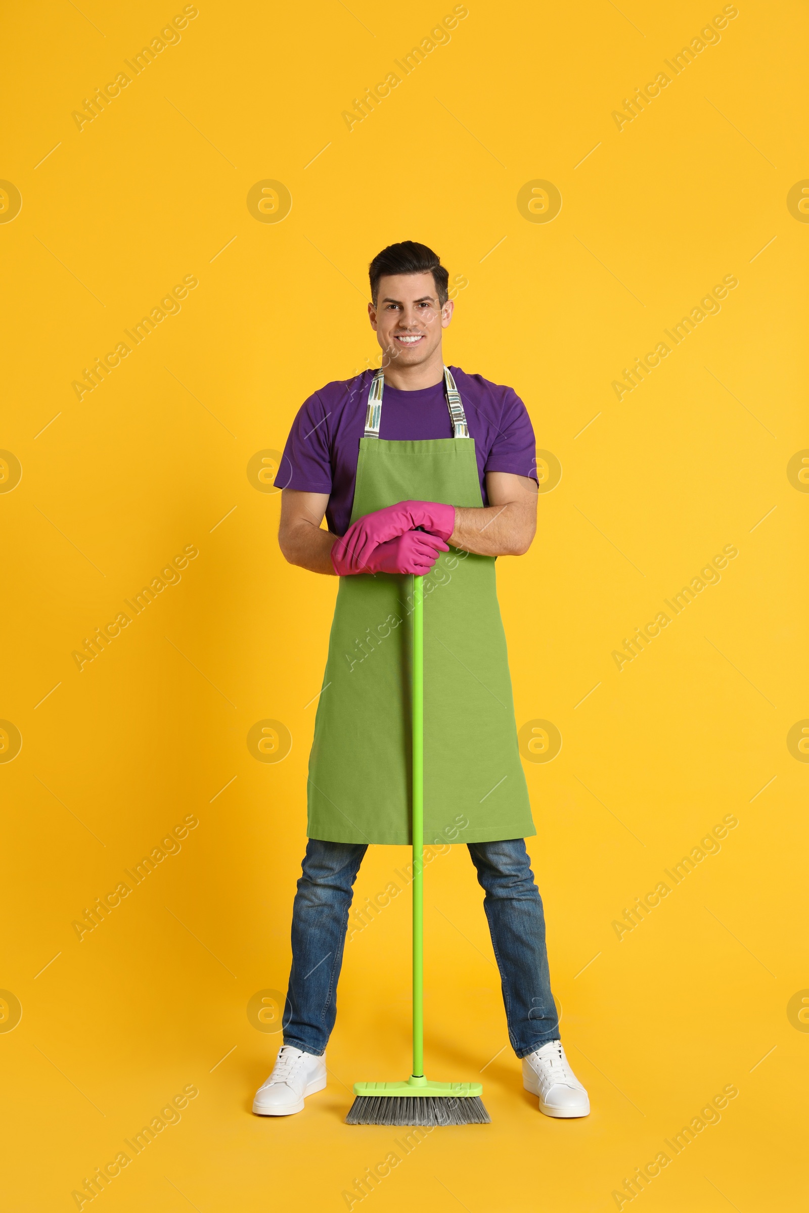 Photo of Man with green broom on orange background