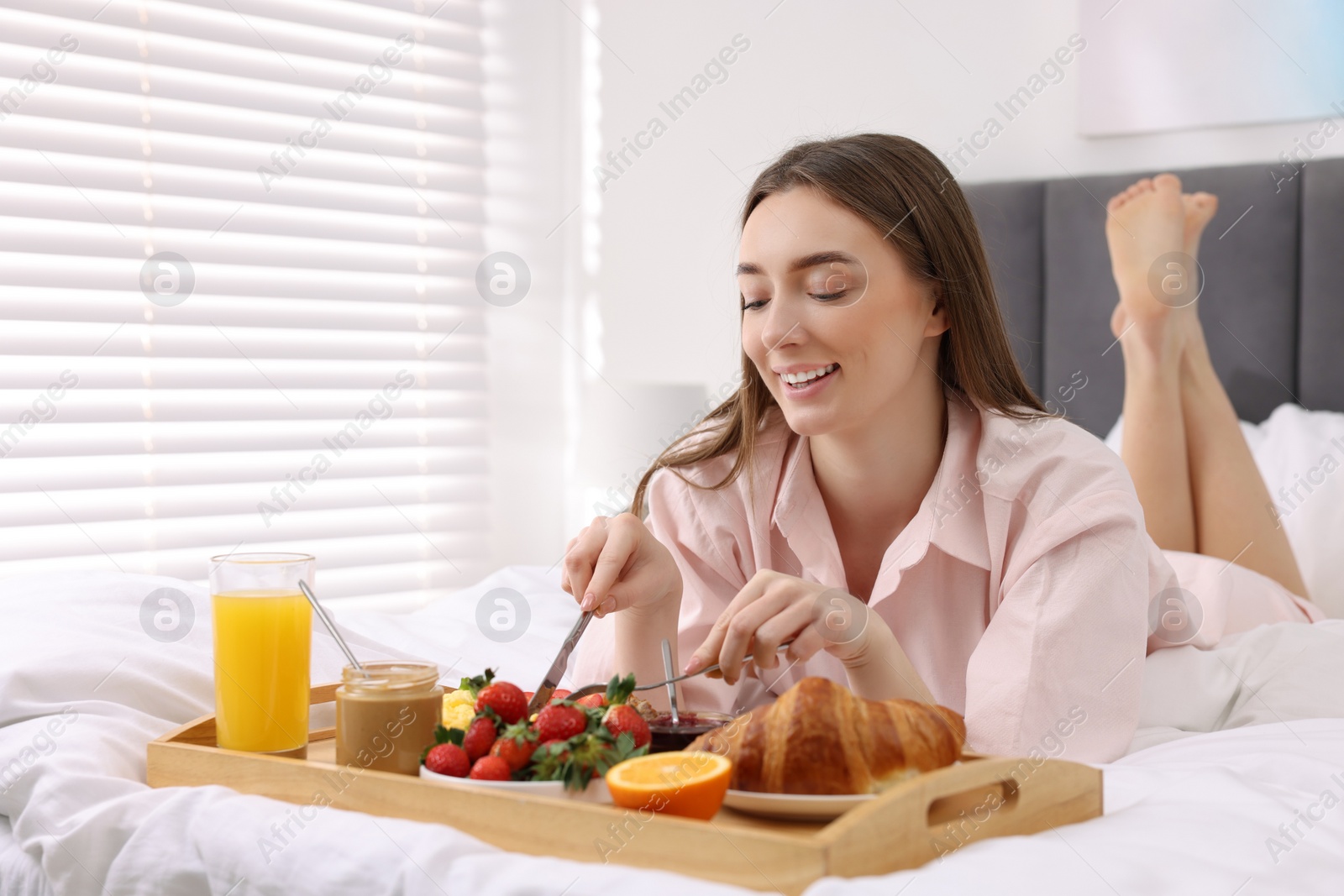 Photo of Smiling woman having tasty breakfast on bed. Space for text