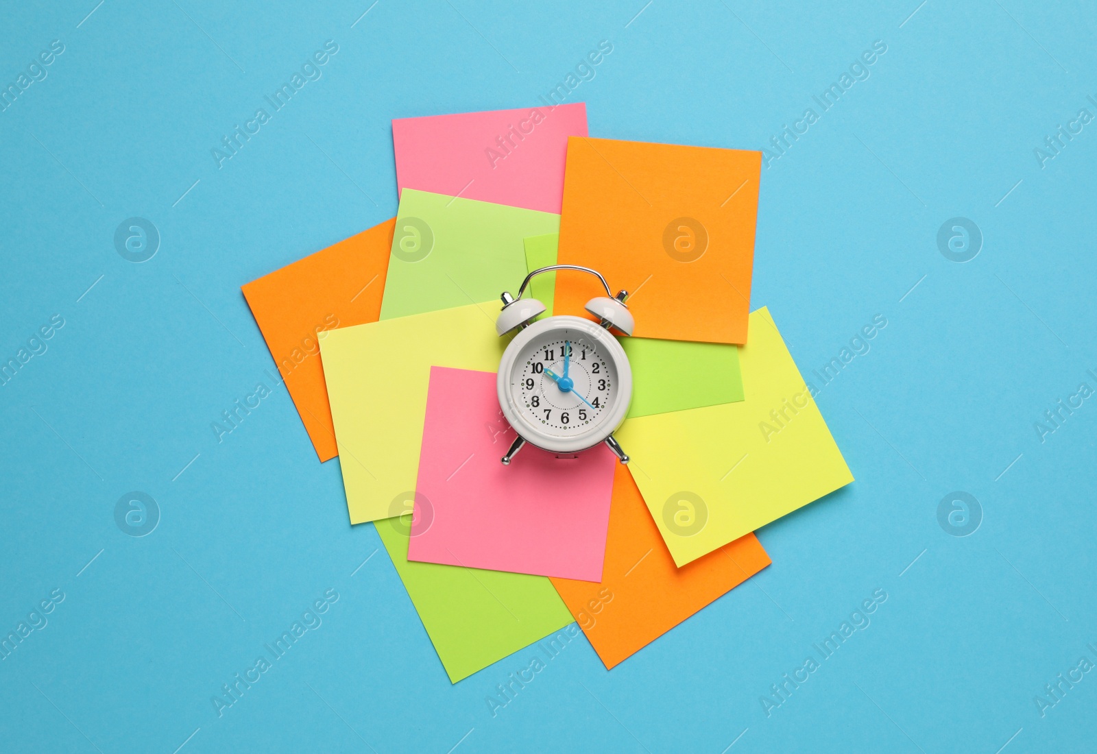 Photo of Alarm clock and blank reminder notes on light blue background, flat lay