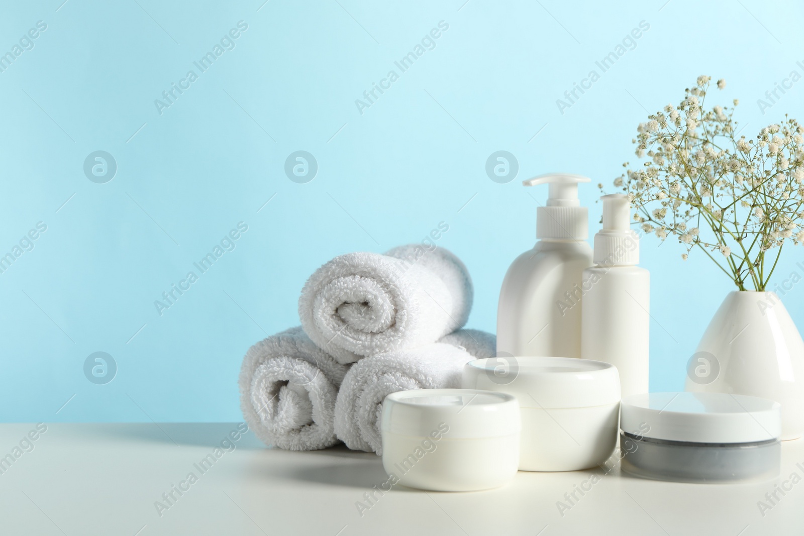 Photo of Different bath accessories and gypsophila on white table against light blue background. Space for text