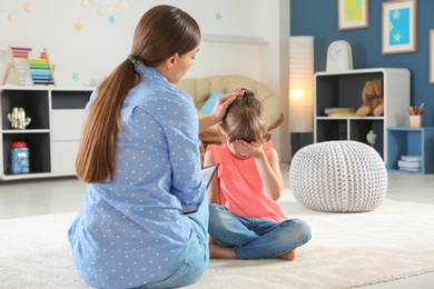 Female psychologist calming cute little girl in office