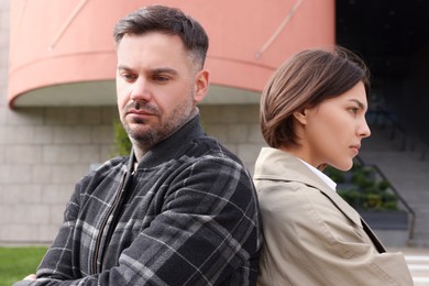 Photo of Man and woman turned away from each other outdoors. Relationship problems