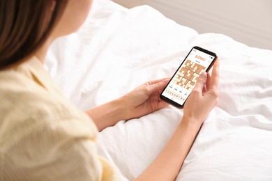 Image of Woman playing sudoku game on smartphone indoors, closeup