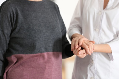 Photo of Elderly woman with female caregiver on blurred background, closeup view