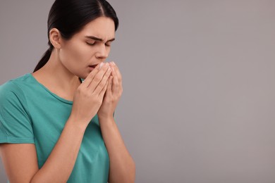Woman coughing on grey background, space for text. Cold symptoms