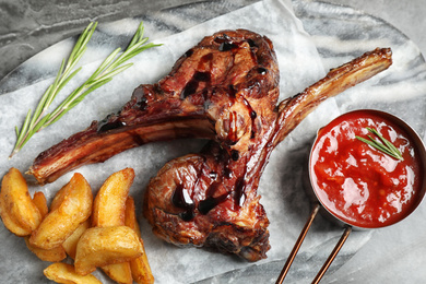 Photo of Delicious grilled ribs served on grey table, flat lay