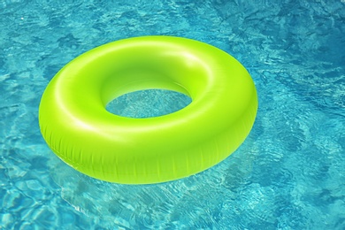 Bright inflatable ring floating in swimming pool on sunny day