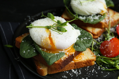 Photo of Delicious poached egg sandwich served on slate board, closeup