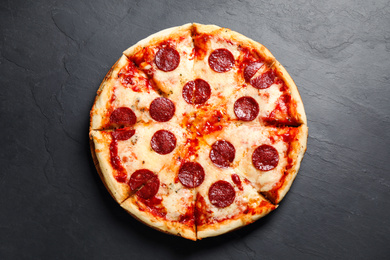Photo of Hot delicious pepperoni pizza on dark table, top view