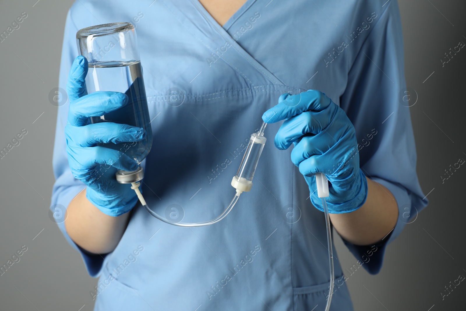 Photo of Nurse with IV infusion set on grey background, closeup
