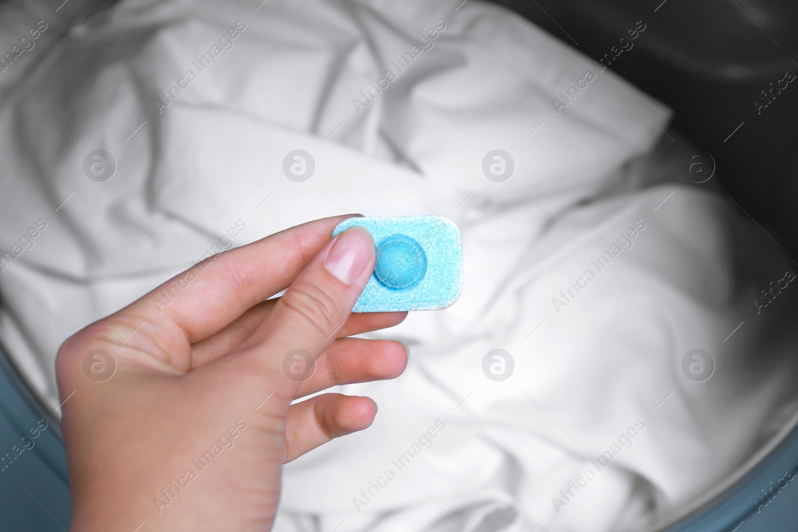 Photo of Woman putting water softener tablet into washing machine, closeup