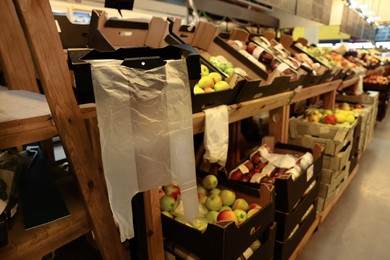 Plastic bags near rack with fruits in supermarket