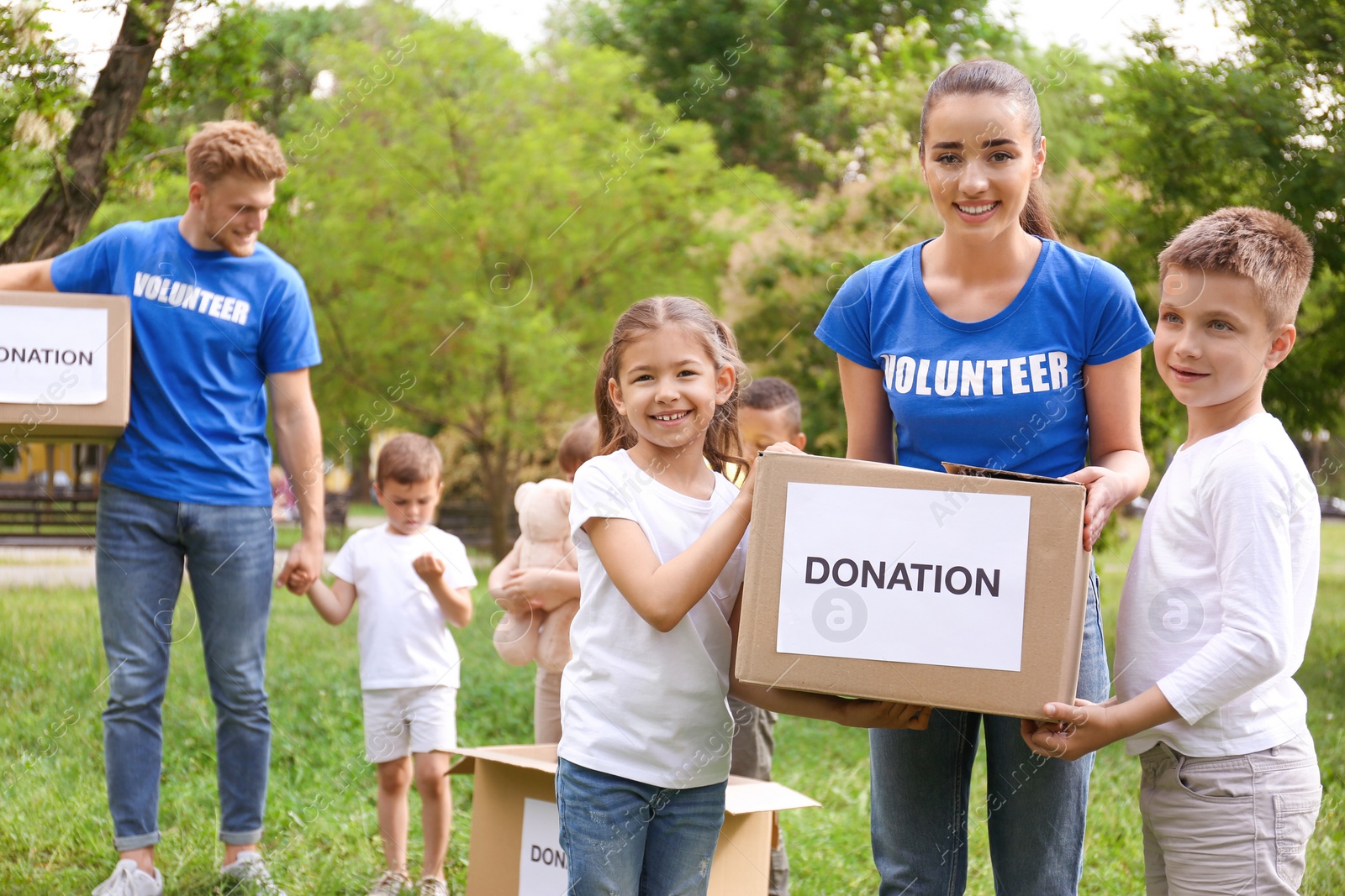 Photo of Volunteers and kids with donation boxes in park