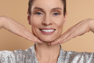 Woman massaging her face on beige background