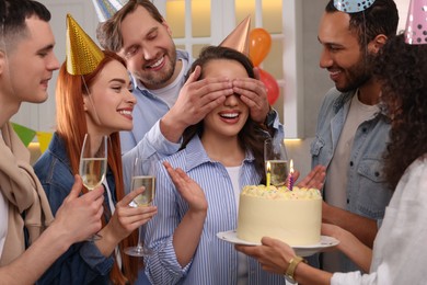 Photo of Happy friends with tasty cake celebrating birthday indoors