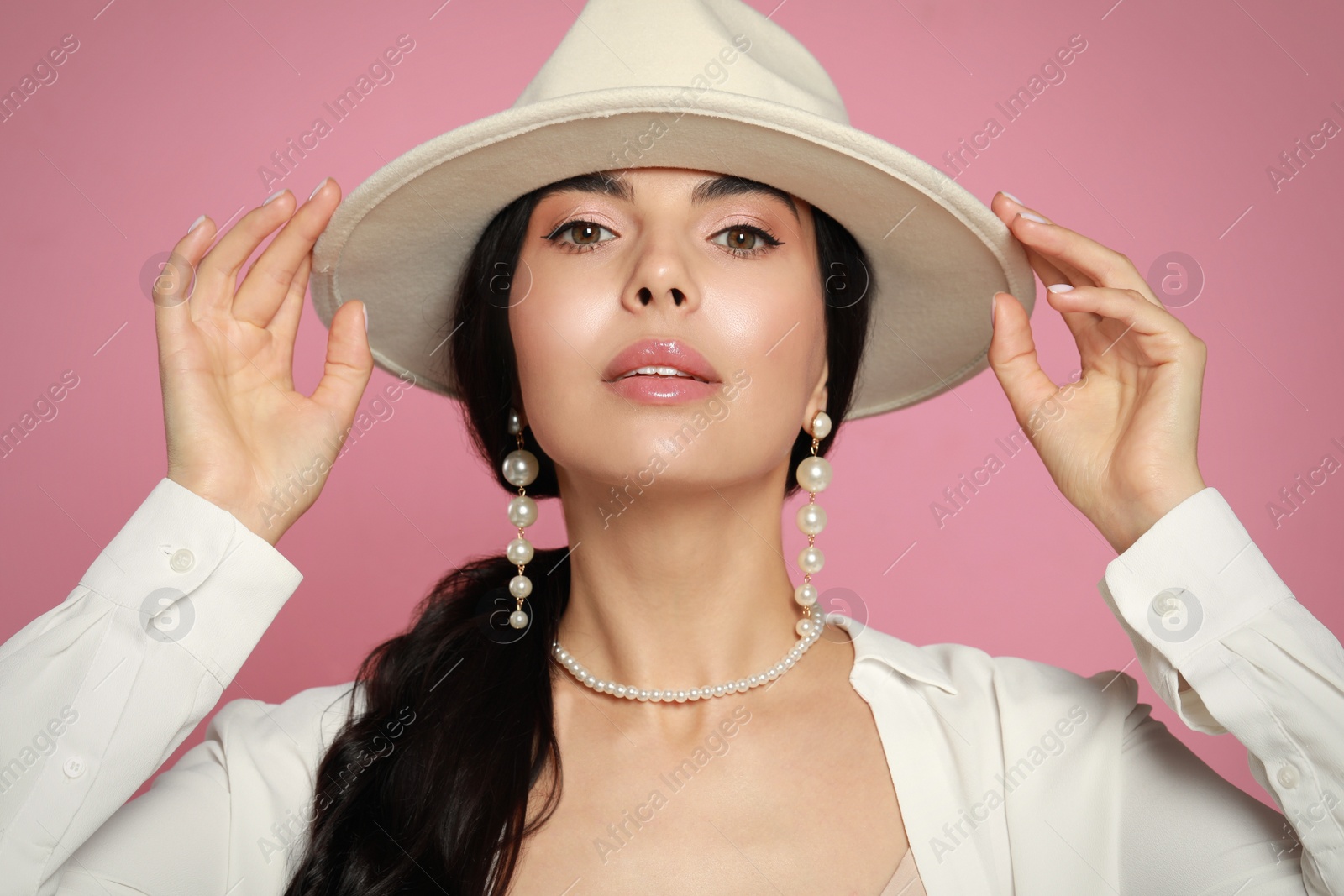 Photo of Young woman wearing elegant pearl jewelry on pink background