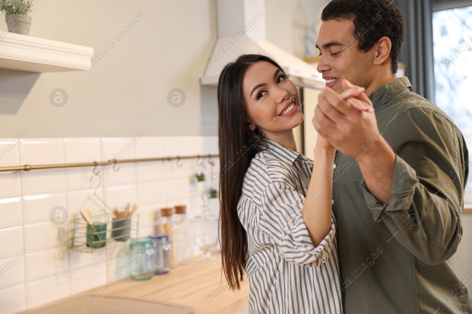 Photo of Lovely young interracial couple dancing at home. Space for text