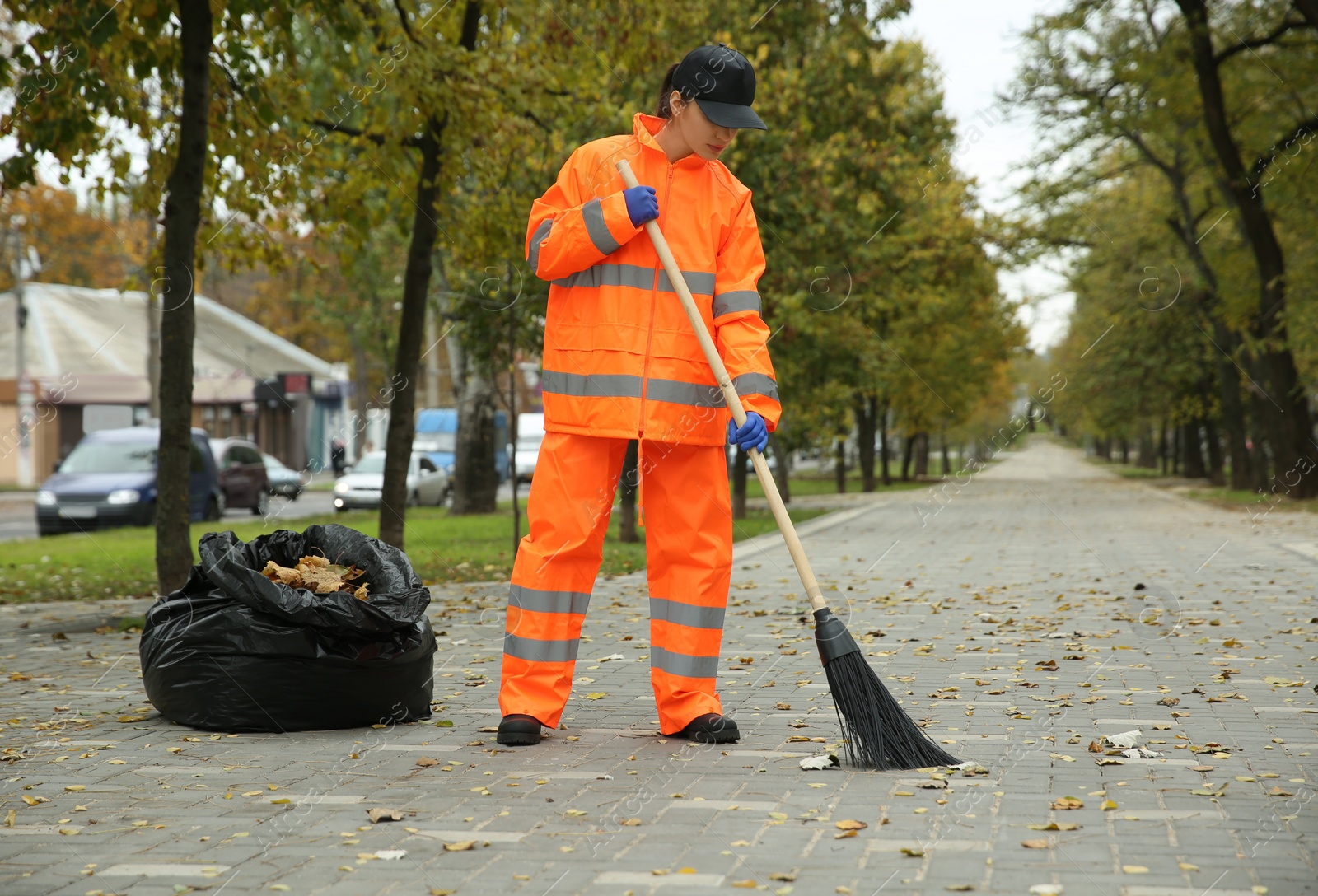 Photo of Street cleaner sweeping fallen leaves outdoors on autumn day