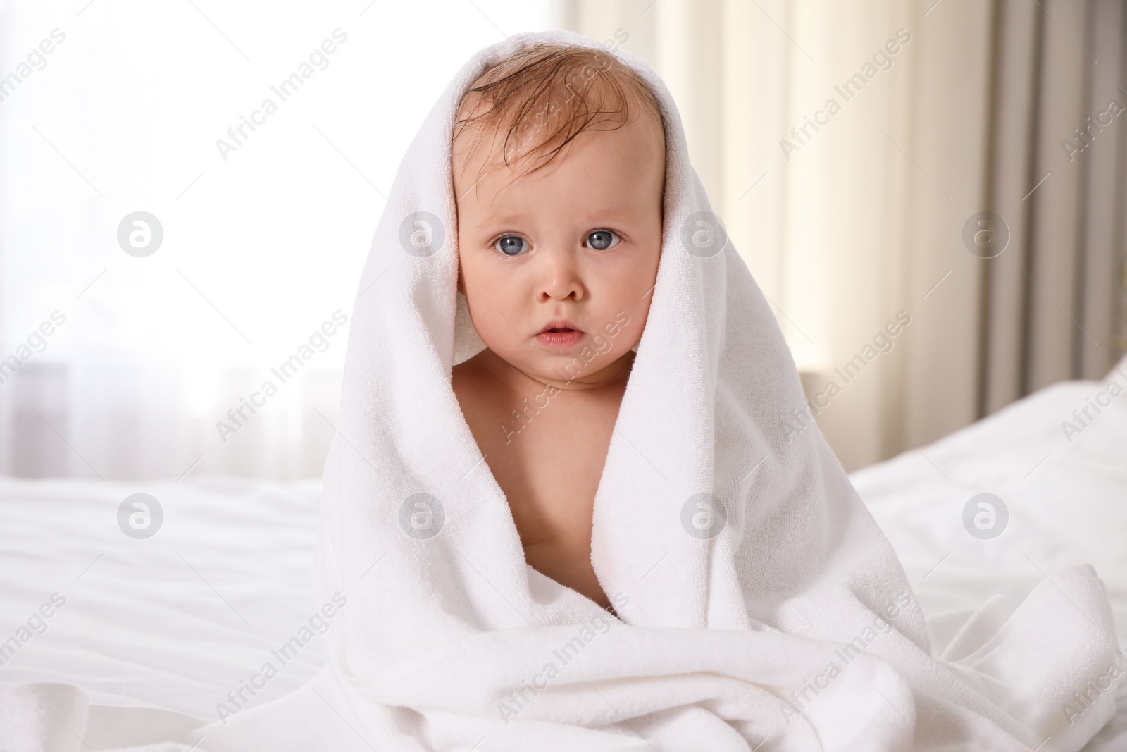 Photo of Cute little baby with soft towel on bed after bath