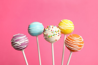 Photo of Many bright delicious cake pops on color background