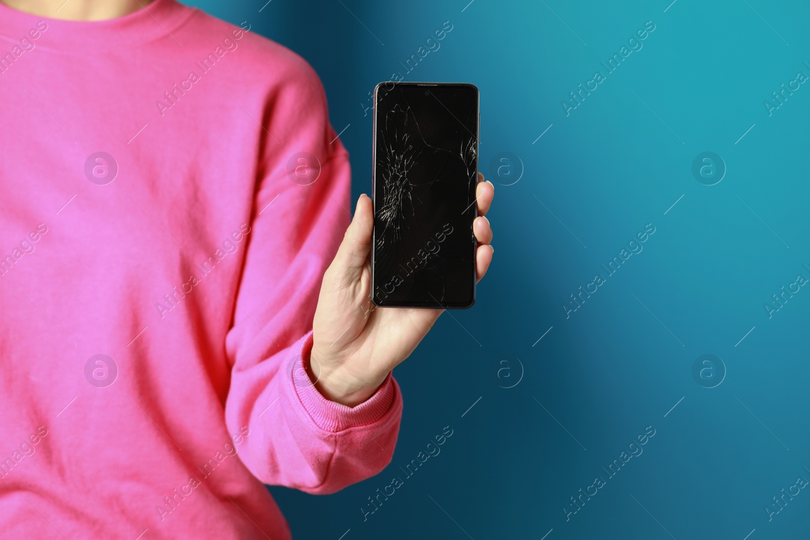 Photo of Woman showing damaged smartphone on light blue background, closeup. Device repairing