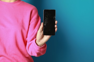 Photo of Woman showing damaged smartphone on light blue background, closeup. Device repairing