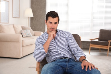 Portrait on handsome young man sitting in chair indoors