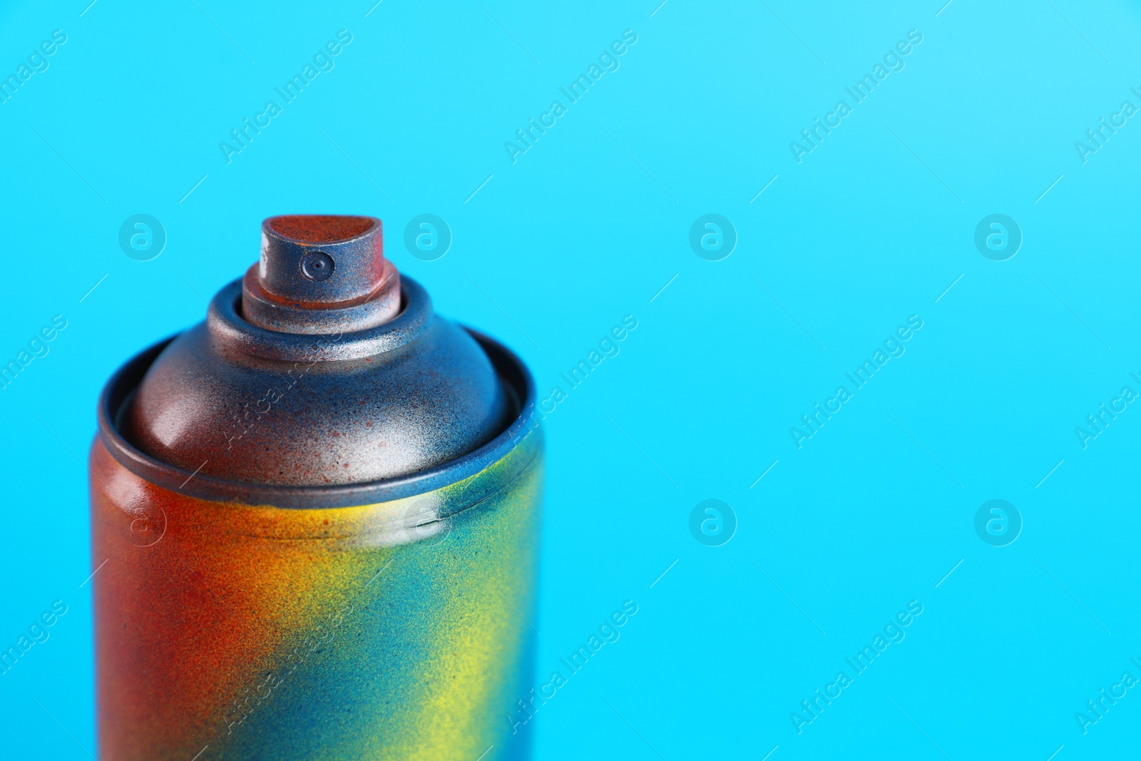 Photo of Used can of spray paint on light blue background, closeup. Space for text