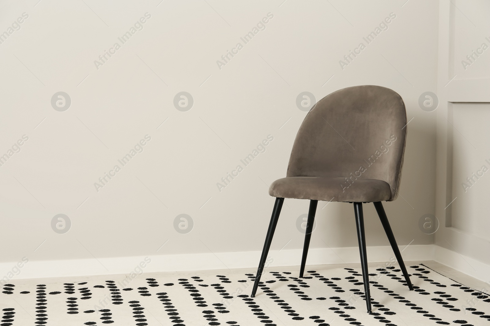 Photo of Stylish grey chair near light wall in room. Space for text