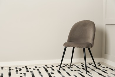 Photo of Stylish grey chair near light wall in room. Space for text