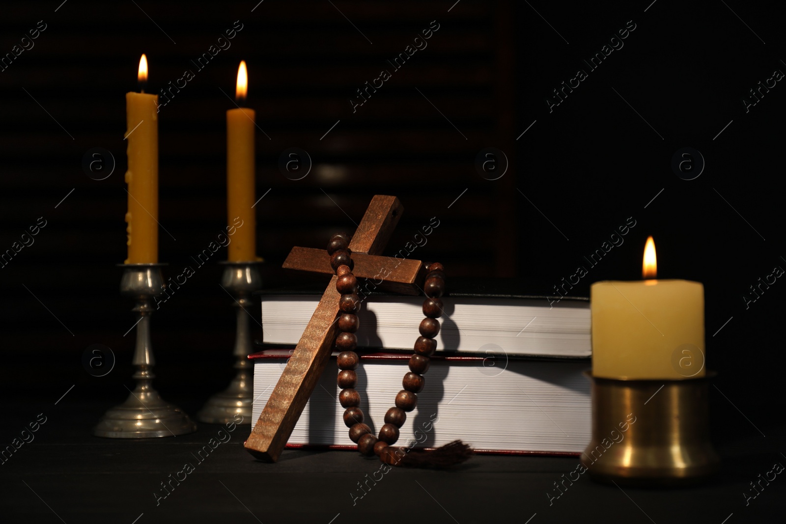 Photo of Church candles, Bible, rosary beads and cross on wooden table