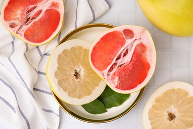Photo of Different tasty pomelo fruits on white tiled table, flat lay