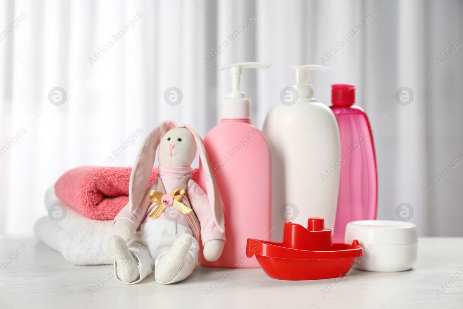 Photo of Baby cosmetic products, toys and towels on table indoors