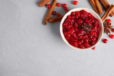 Plate of cranberry sauce with spices on grey background, flat lay. Space for text