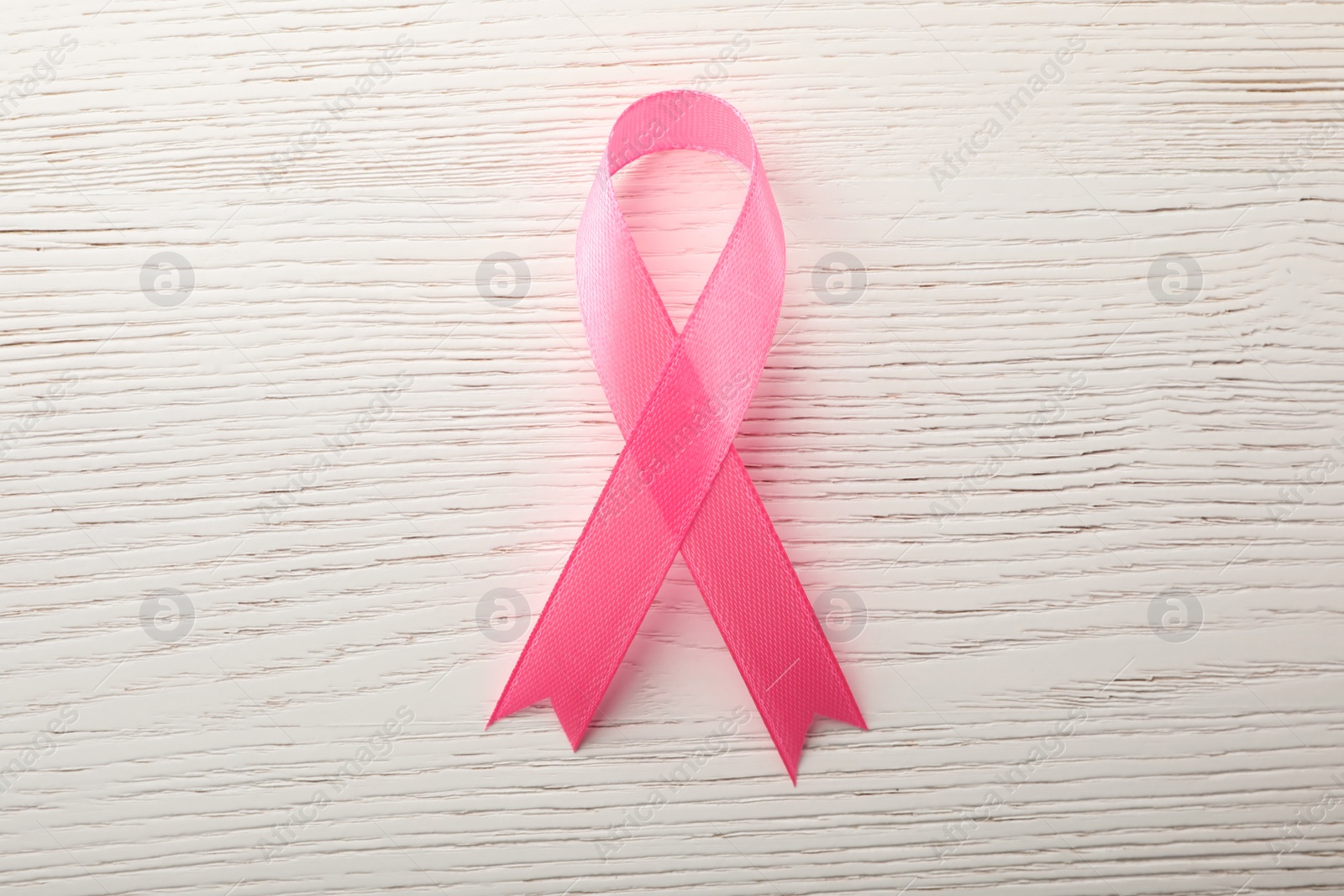 Photo of Pink ribbon on wooden background, top view. Breast cancer awareness concept