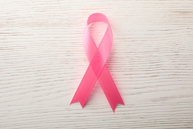 Pink ribbon on wooden background, top view. Breast cancer awareness concept