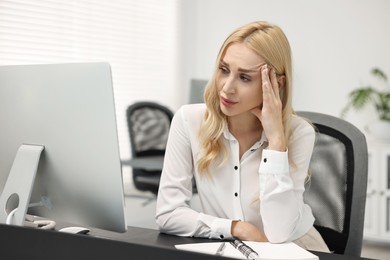 Overwhelmed woman at table with computer in office