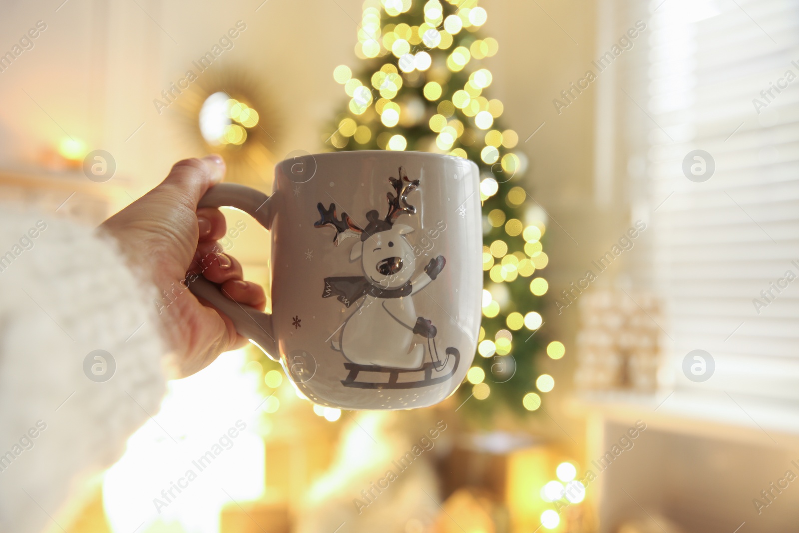 Photo of Woman with cup of drink and blurred Christmas tree on background, closeup