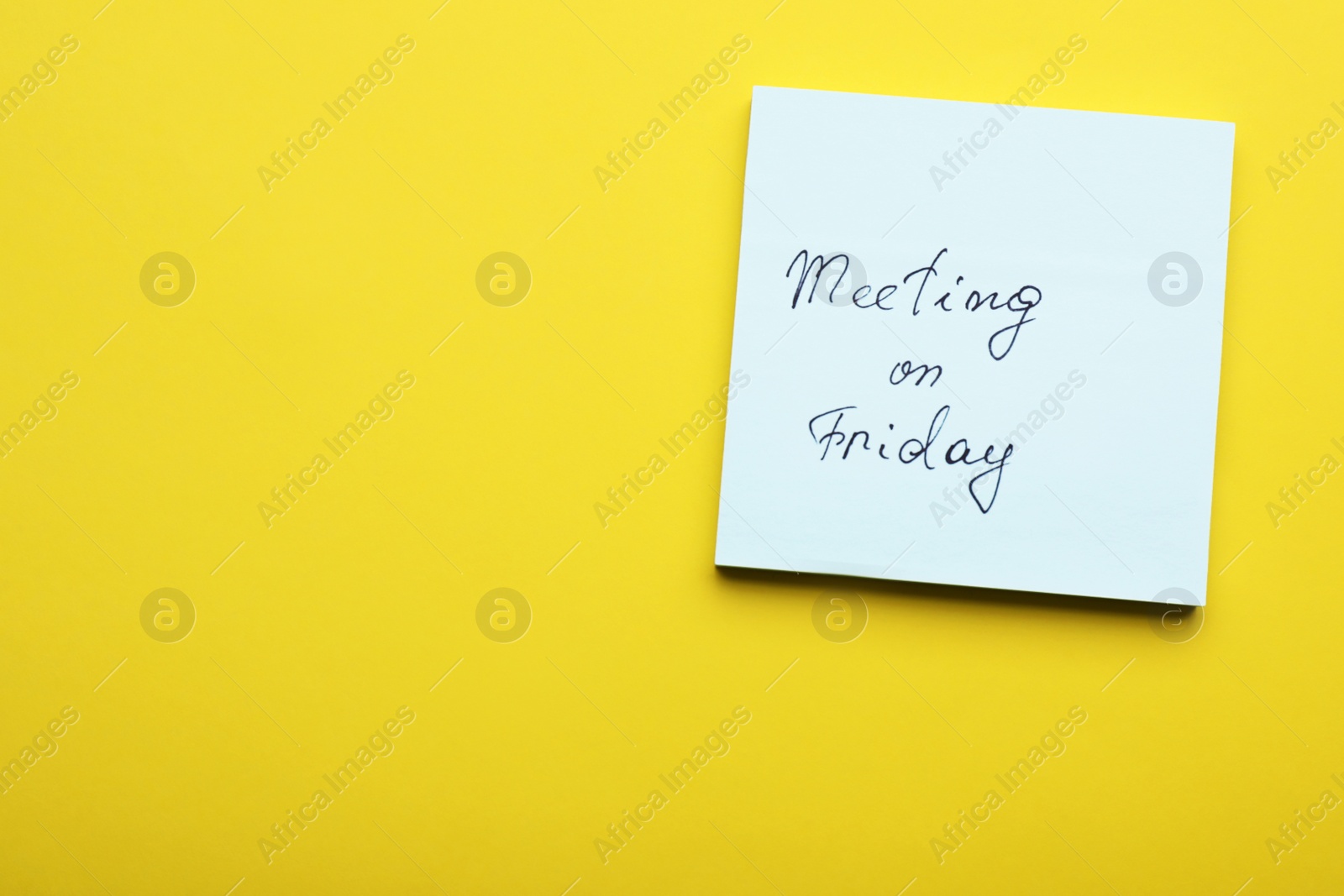 Photo of Paper note with words Meeting on Friday against yellow background, top view. Space for text