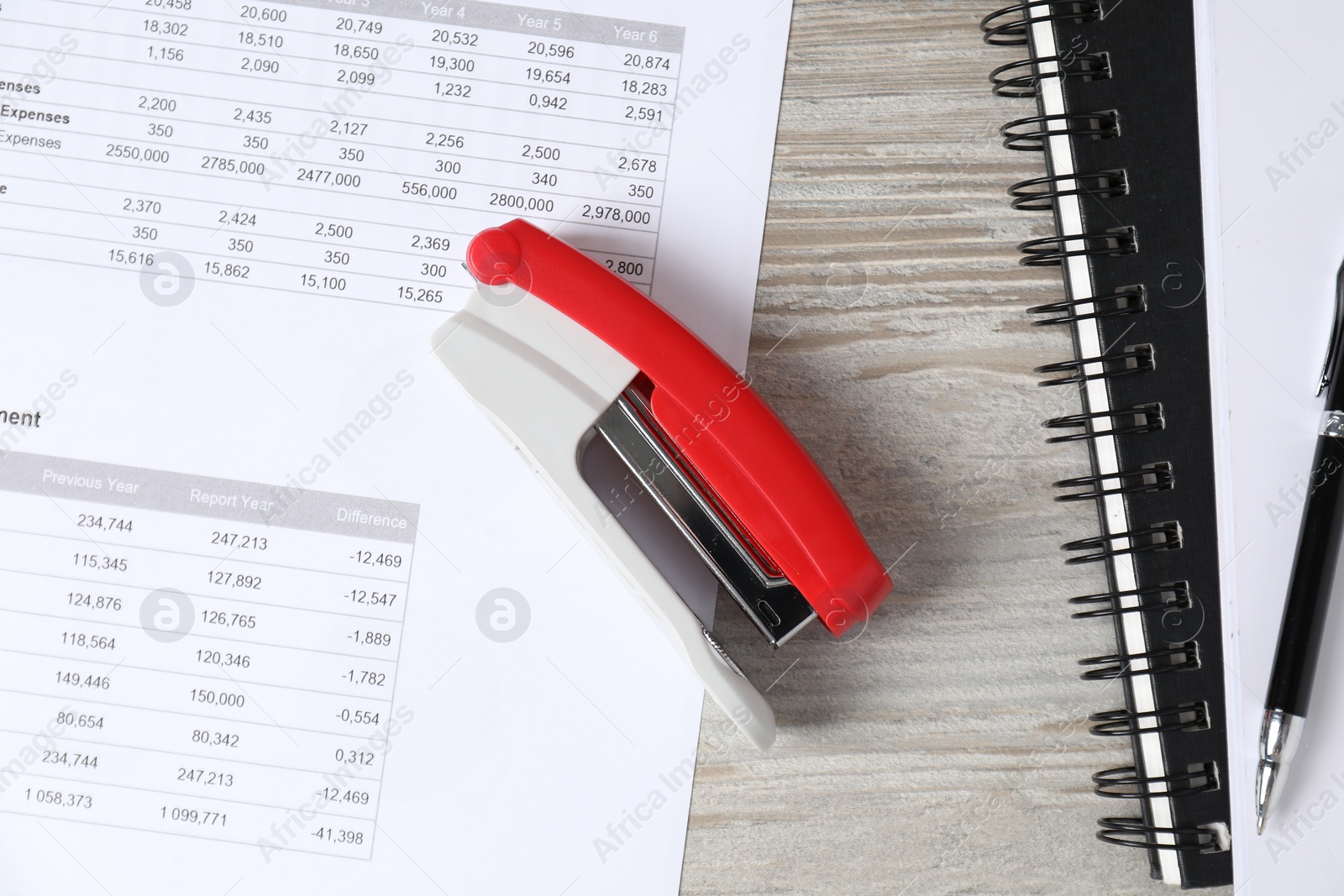 Photo of Stapler, document and notebooks on wooden table, flat lay