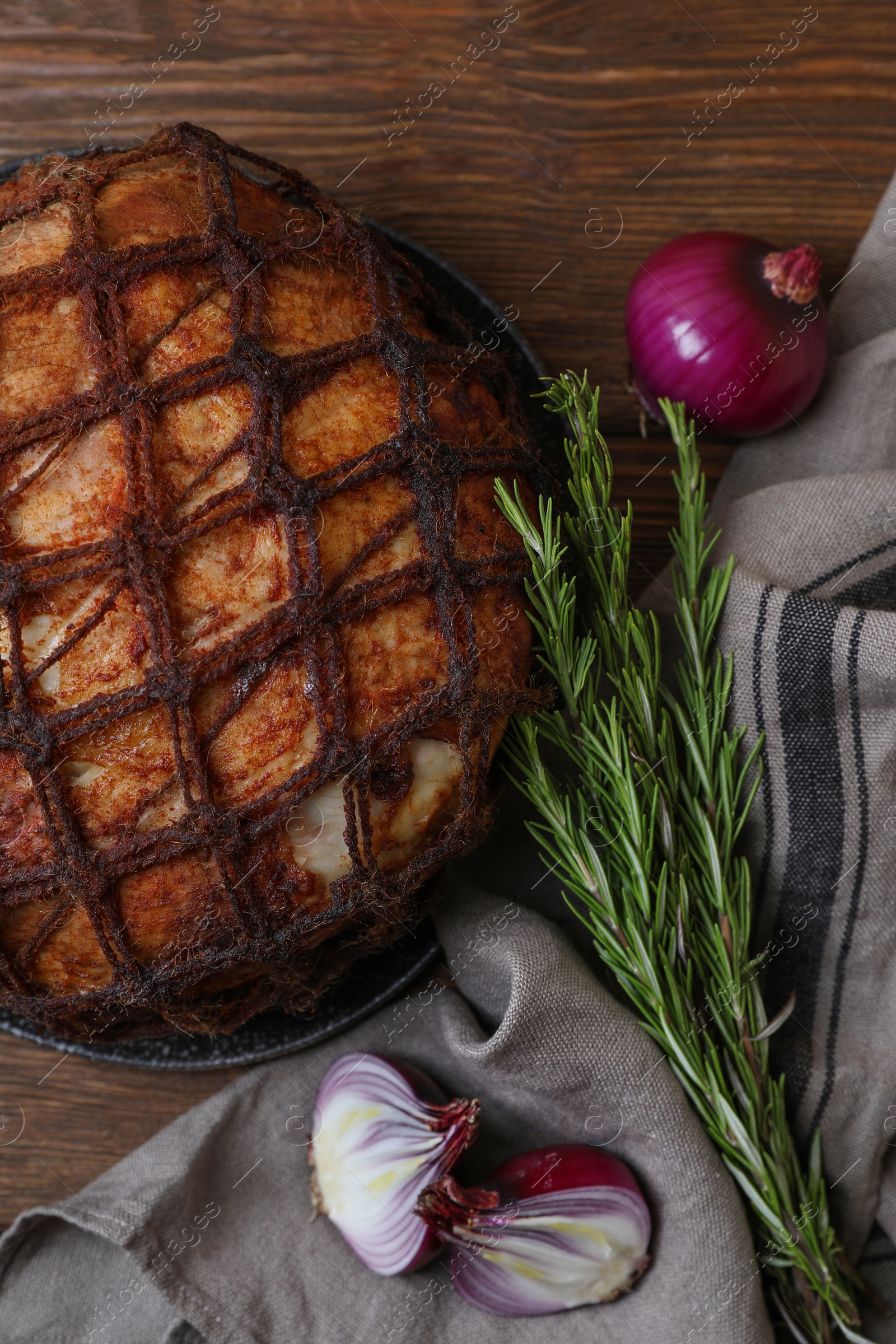 Photo of Delicious baked ham, onion and rosemary on wooden table, flat lay