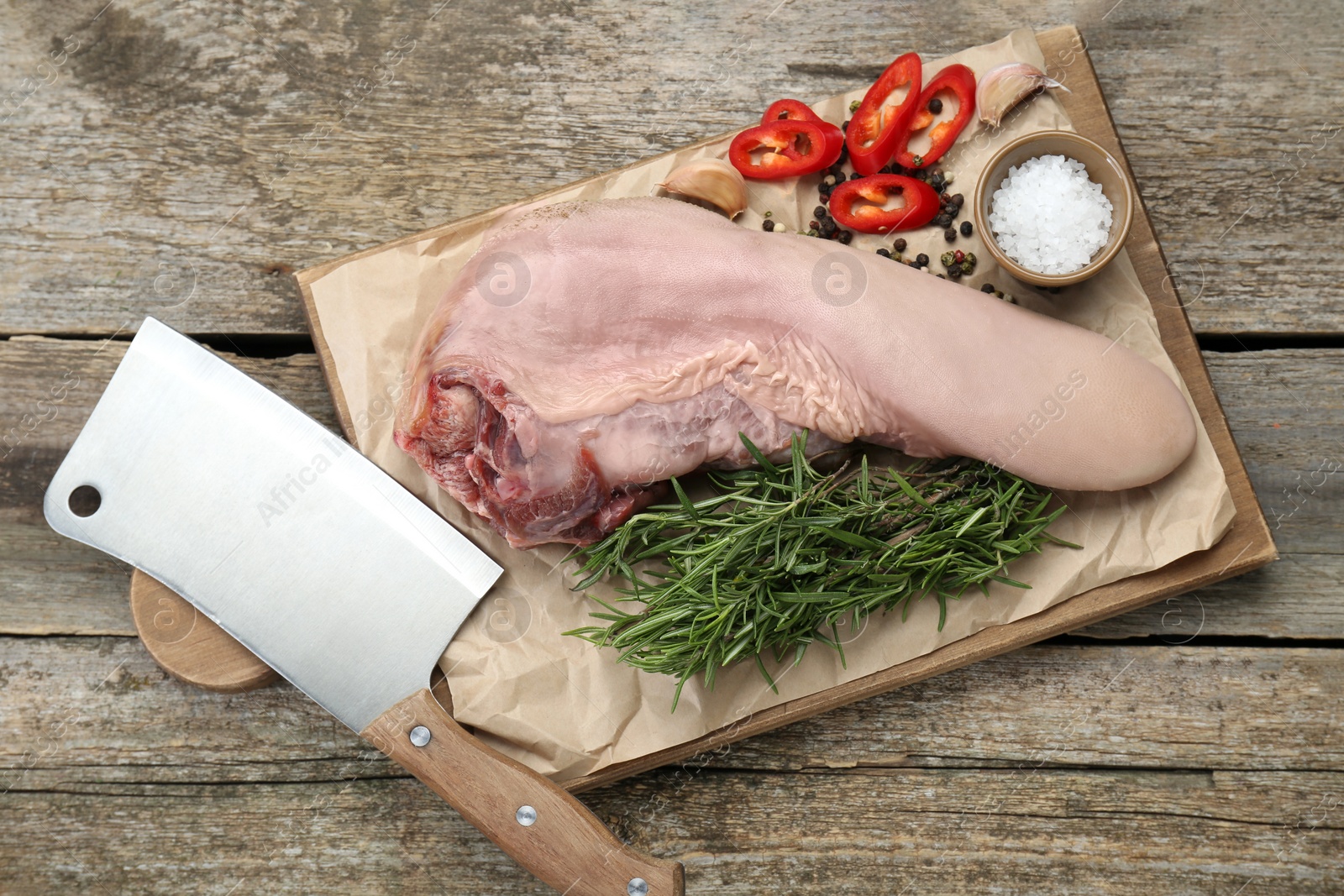 Photo of Board with raw beef tongue and products on wooden table, top view