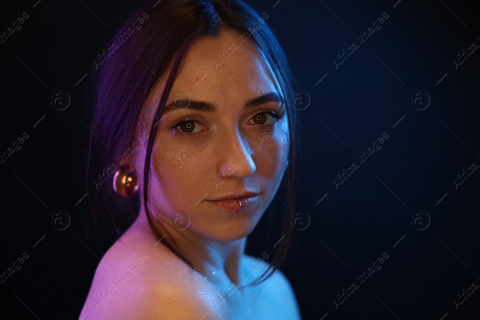 Photo of Portrait of beautiful woman on dark background in neon lights, space for text