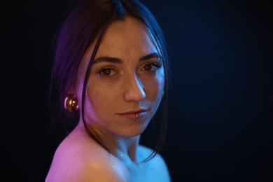 Photo of Portrait of beautiful woman on dark background in neon lights, space for text