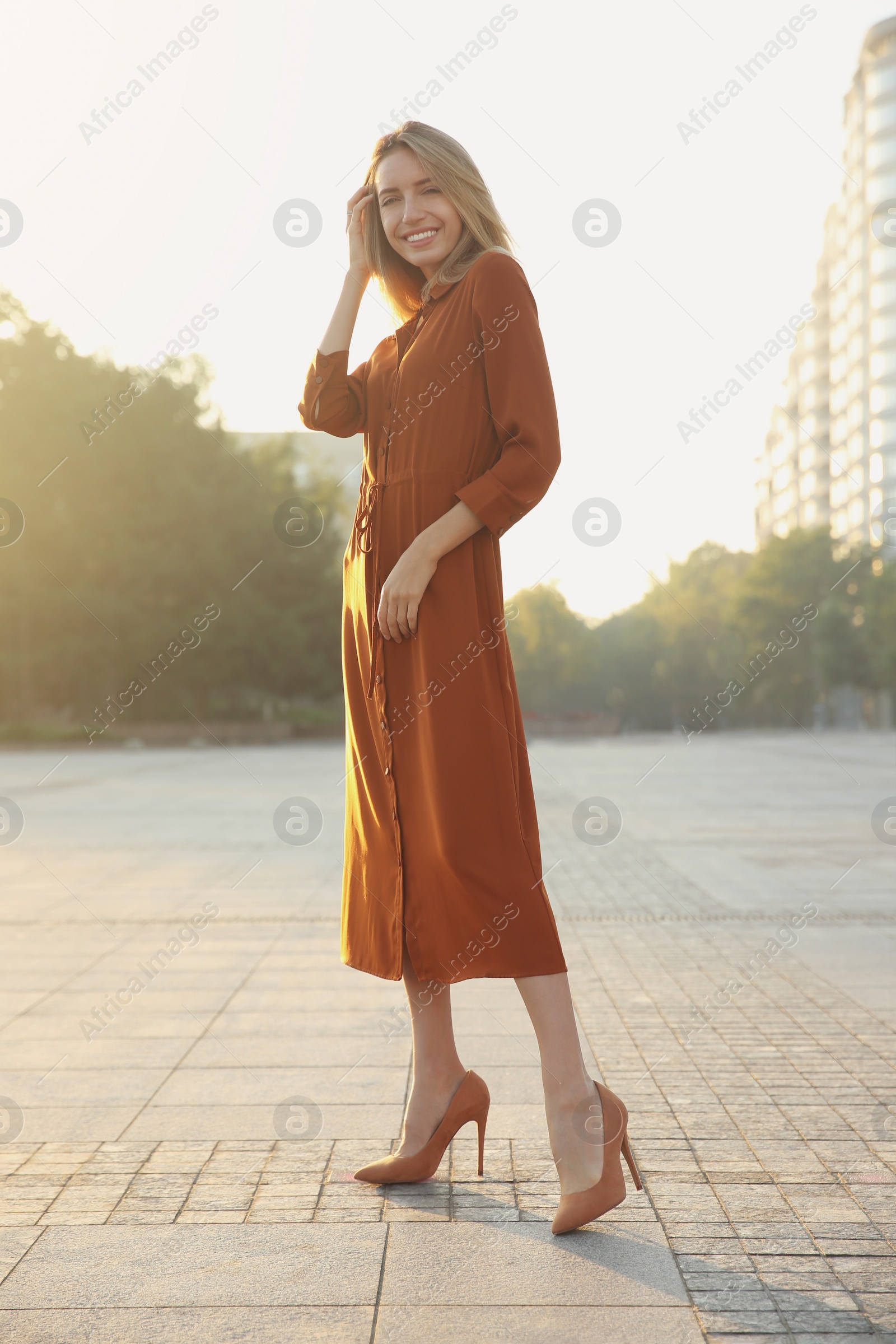 Photo of Beautiful young woman in stylish red dress on city street