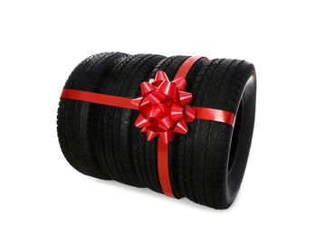 Winter tires with red ribbon on white background