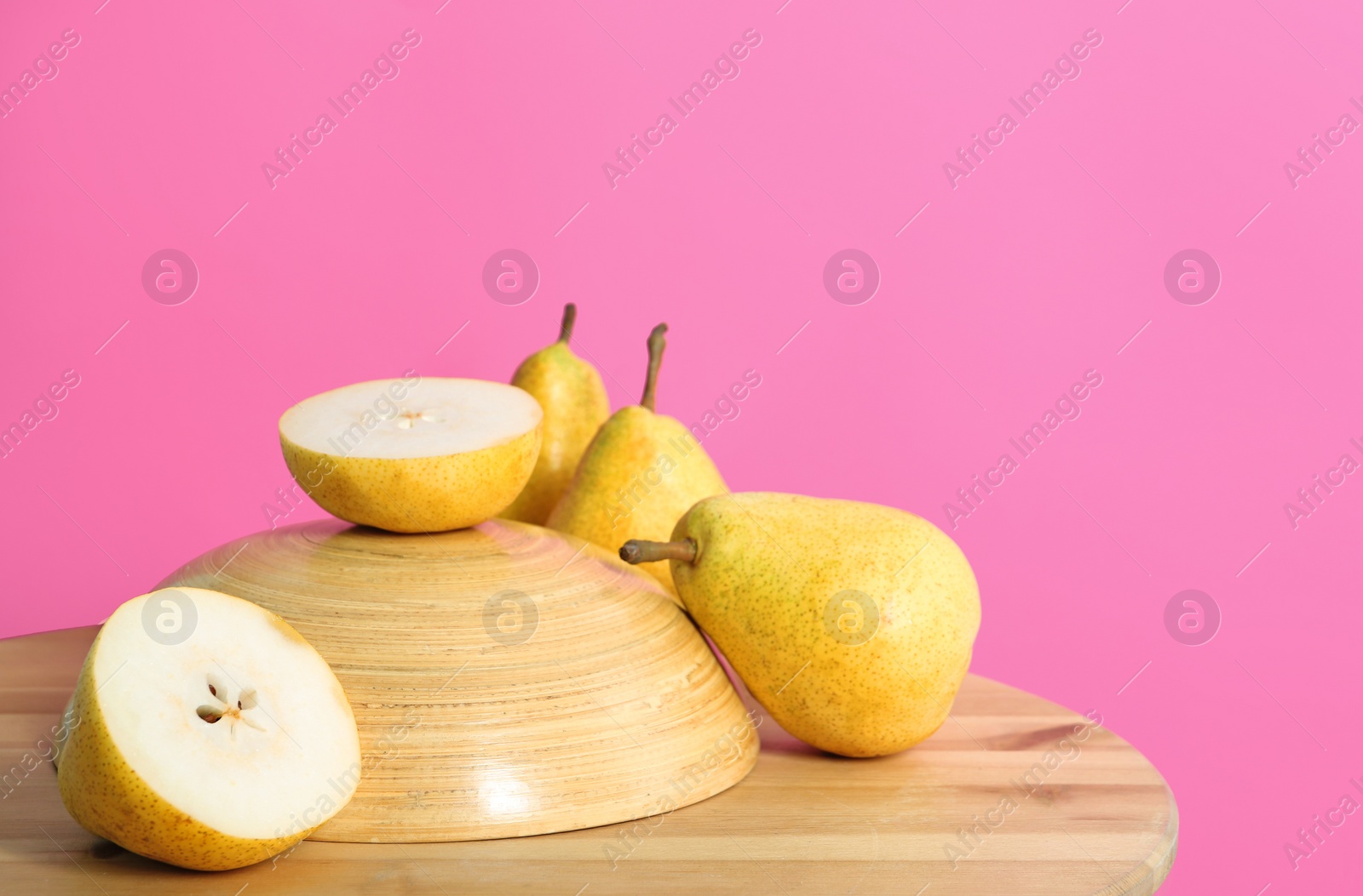 Photo of Fresh ripe pears on wooden table against color background. Space for text